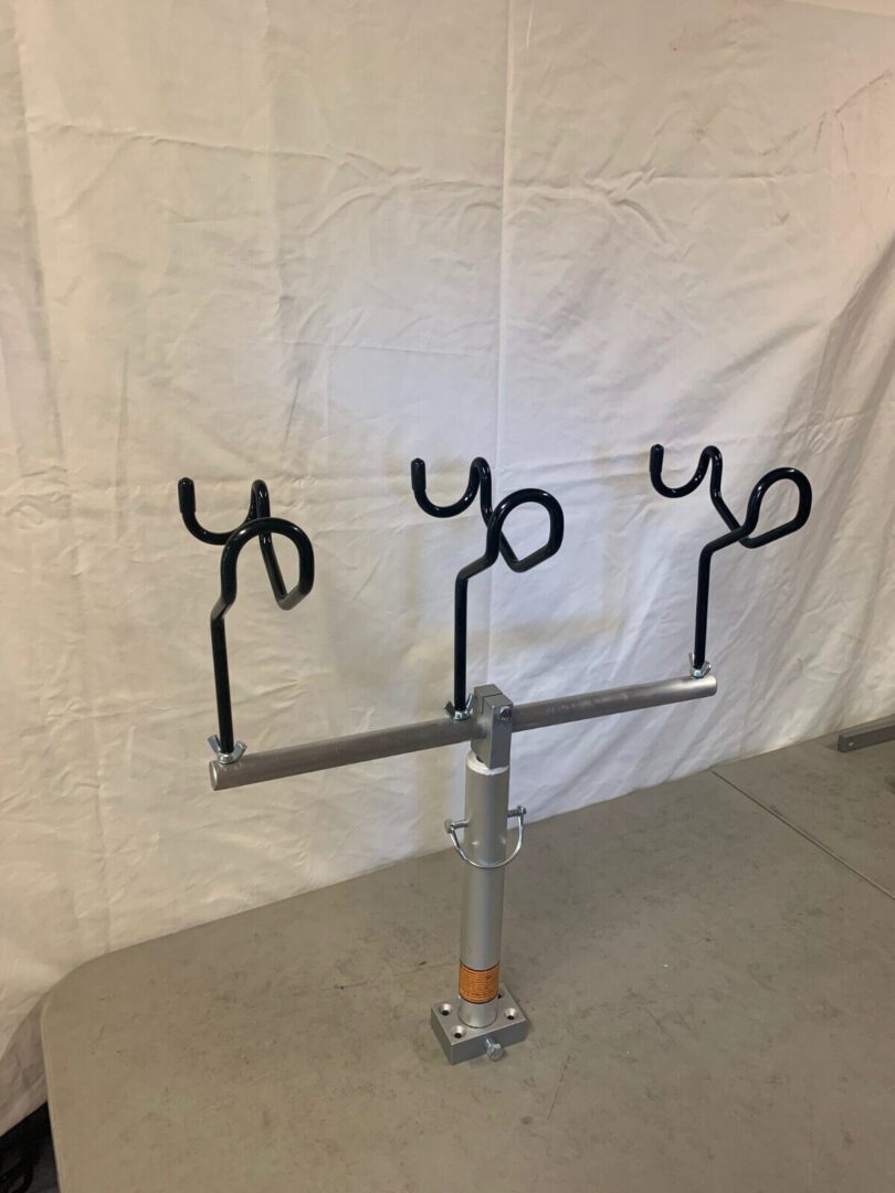 A metal stand with three hooks on it.