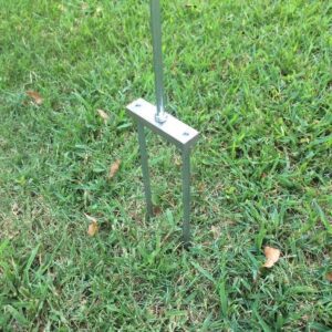 A metal pole with a metal base in the grass.