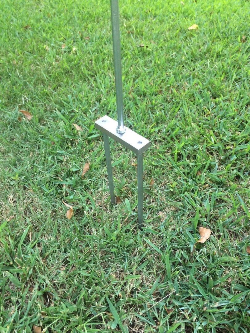 A metal pole with a metal base in the grass.