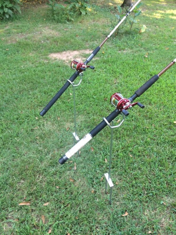 Two fishing rods on a pole in the grass.