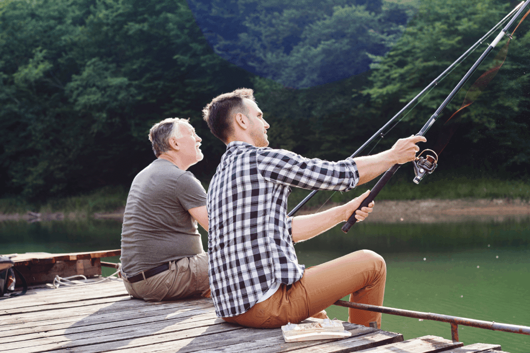 Two men fishing on a pier with trees in the background.